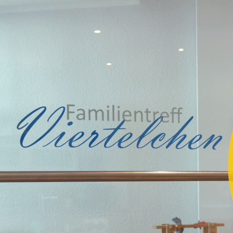 Familientreff Viertelchen Glasfläche mit der Schriftzug "Familientreff Viertelchen" in blauer Schrift.
